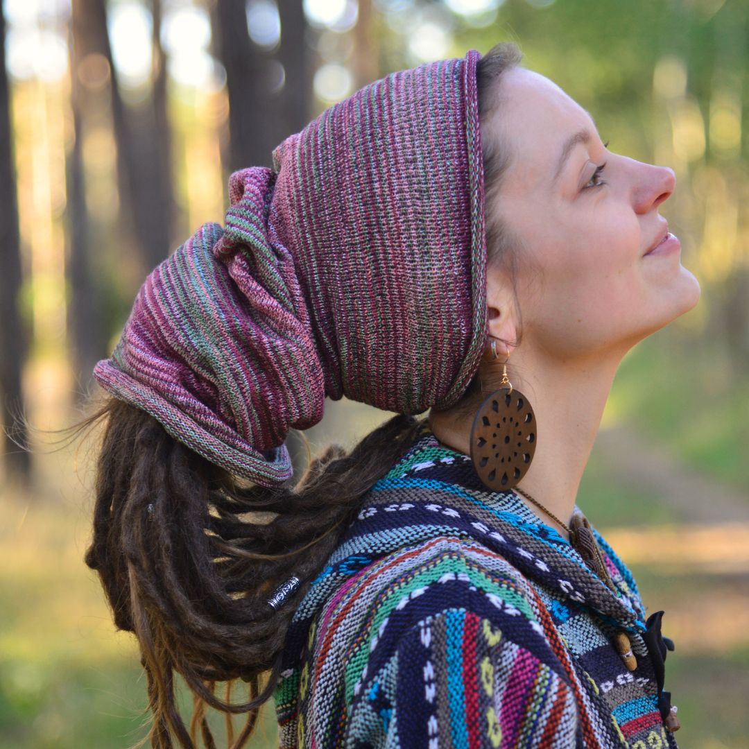 Woman with a colorful headscarf and patterned shawl in a forest setting
