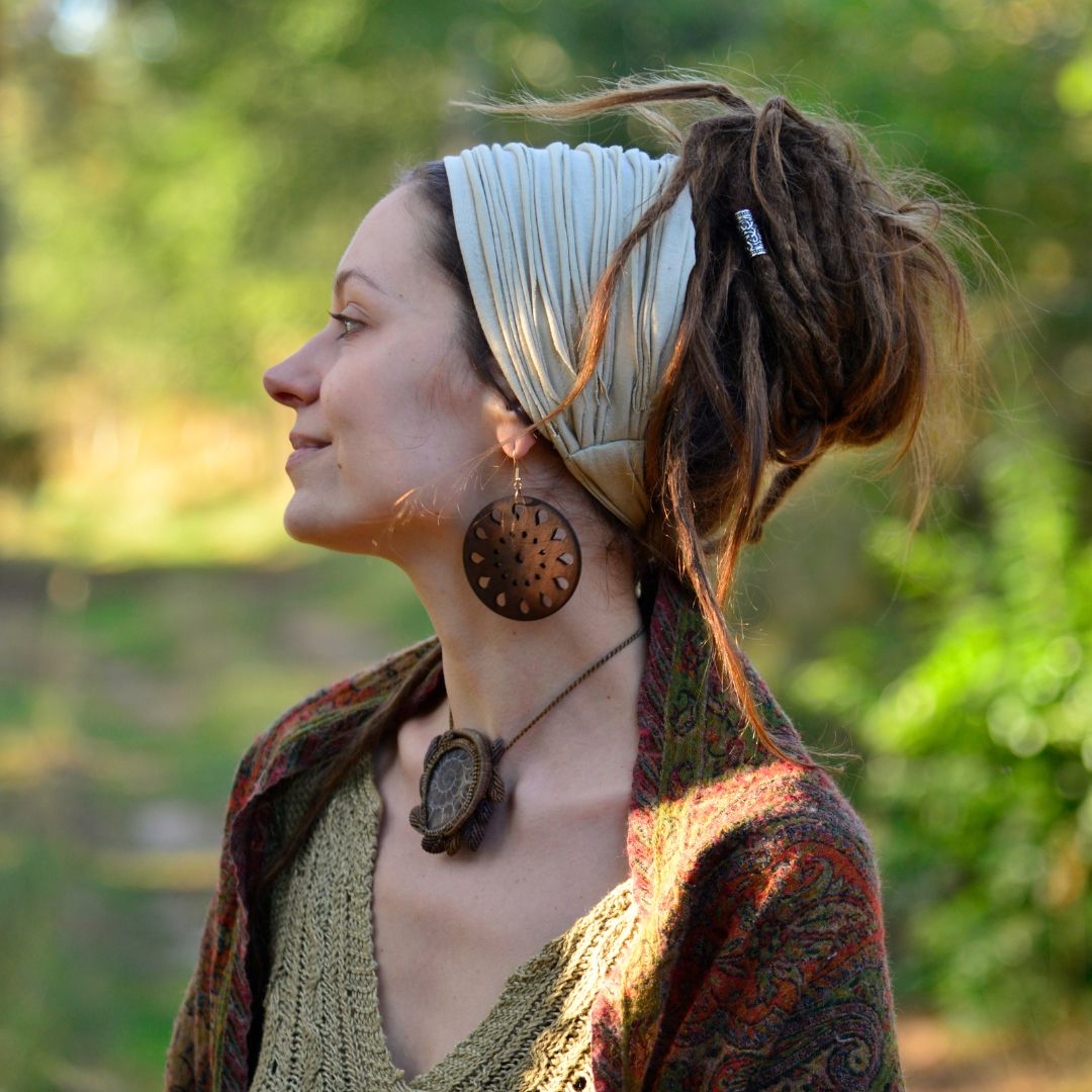 Woman with dreadlocks wearing a headband and earrings outdoors