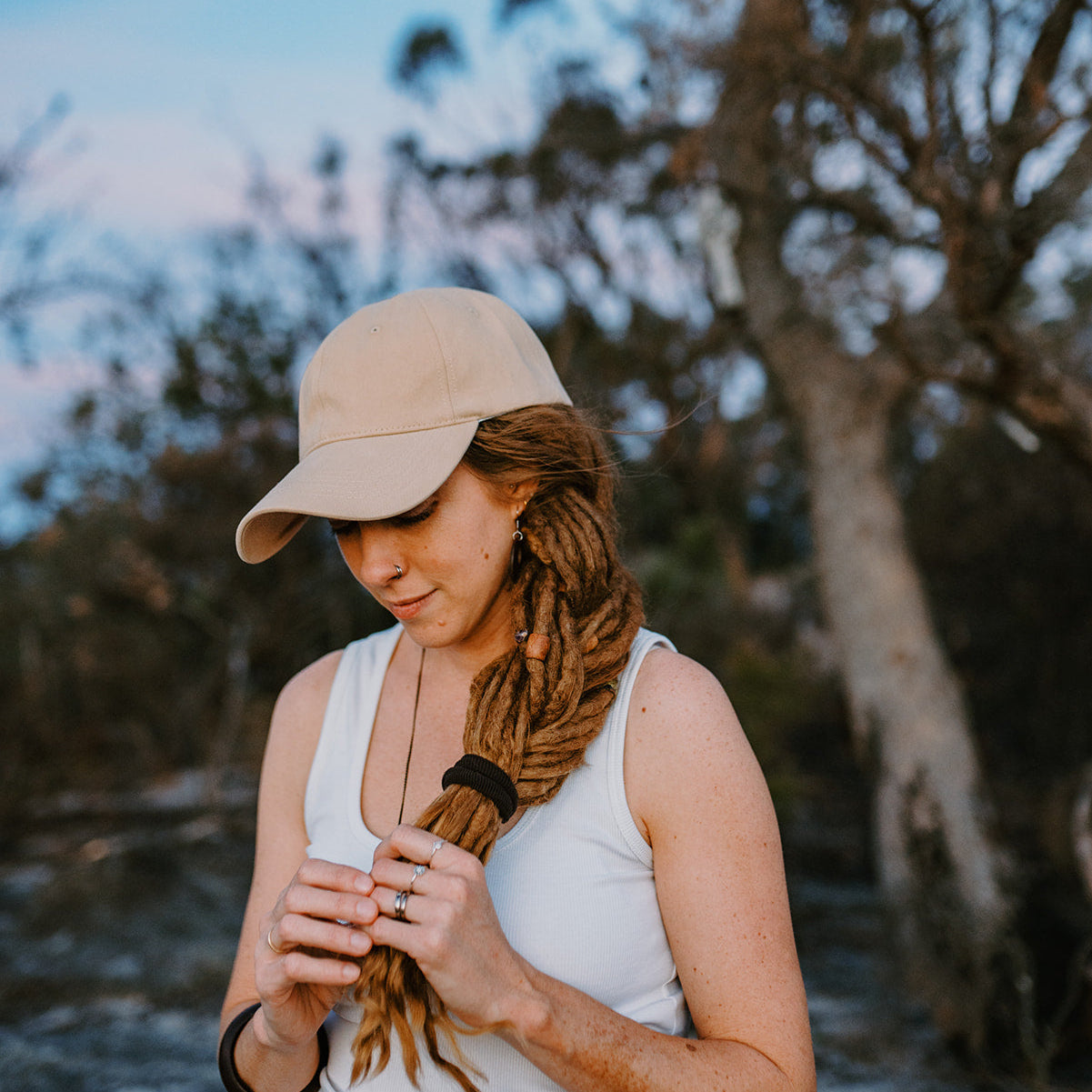Woman with braided hair wearing a beige cap outdoors