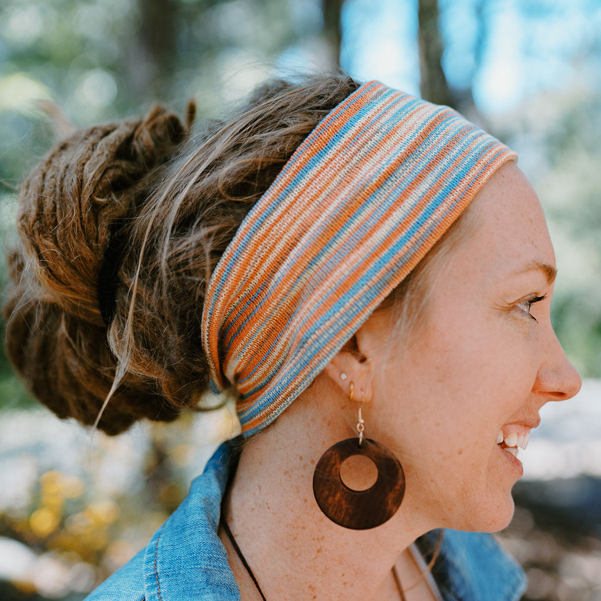 Woman wearing a striped headband and wooden earrings outdoors