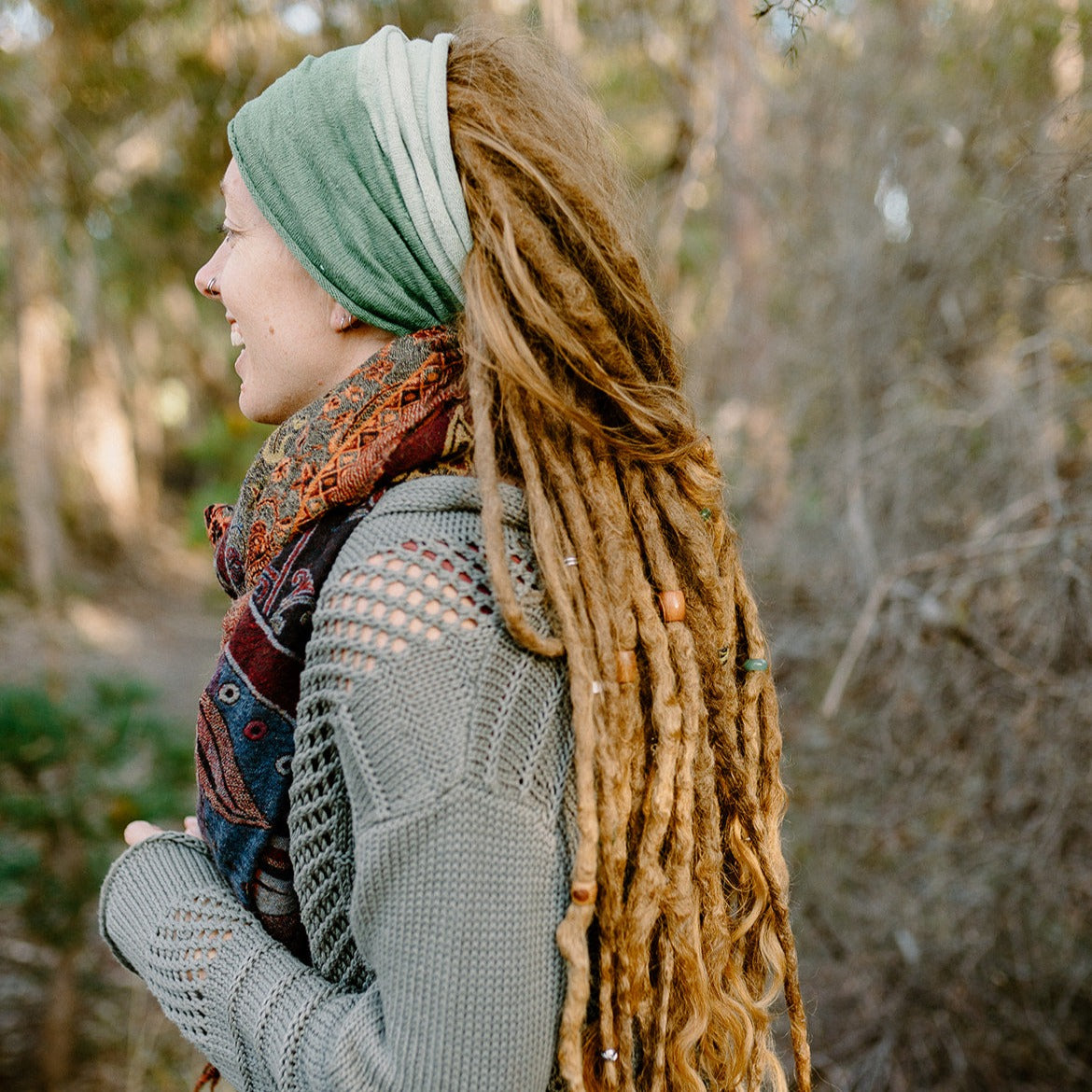 A person wearing a green cotton double loop dread wrap headband.