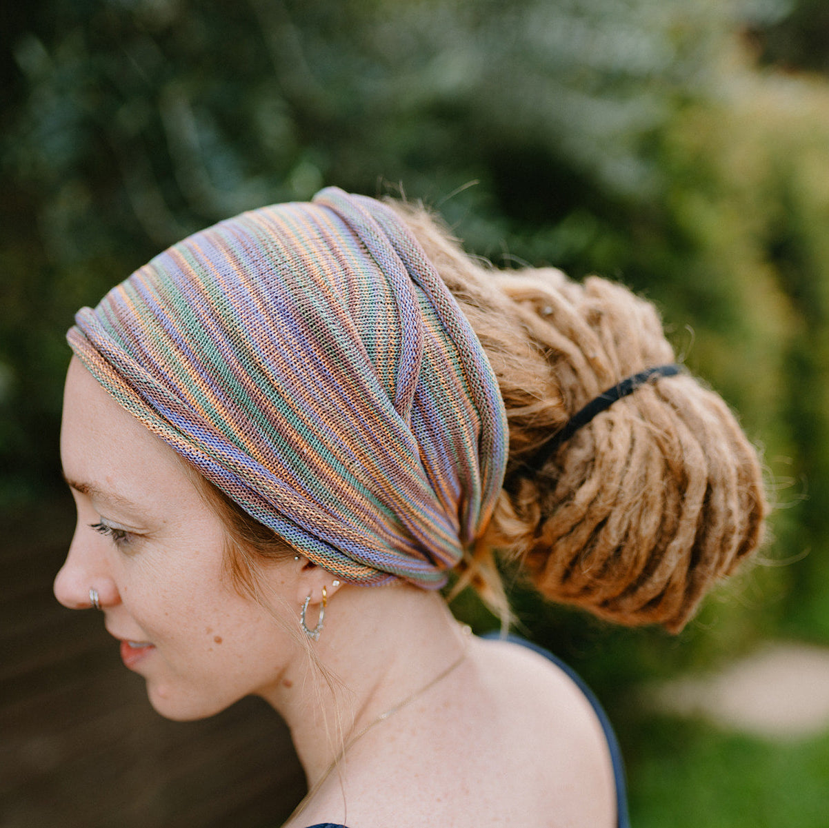 Woman wearing a colorful double loop cotton hair wrap with a blurred natural background