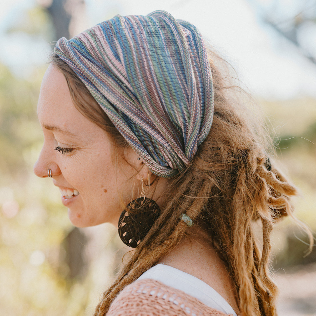 Woman wearing a striped headband with a blurred natural background