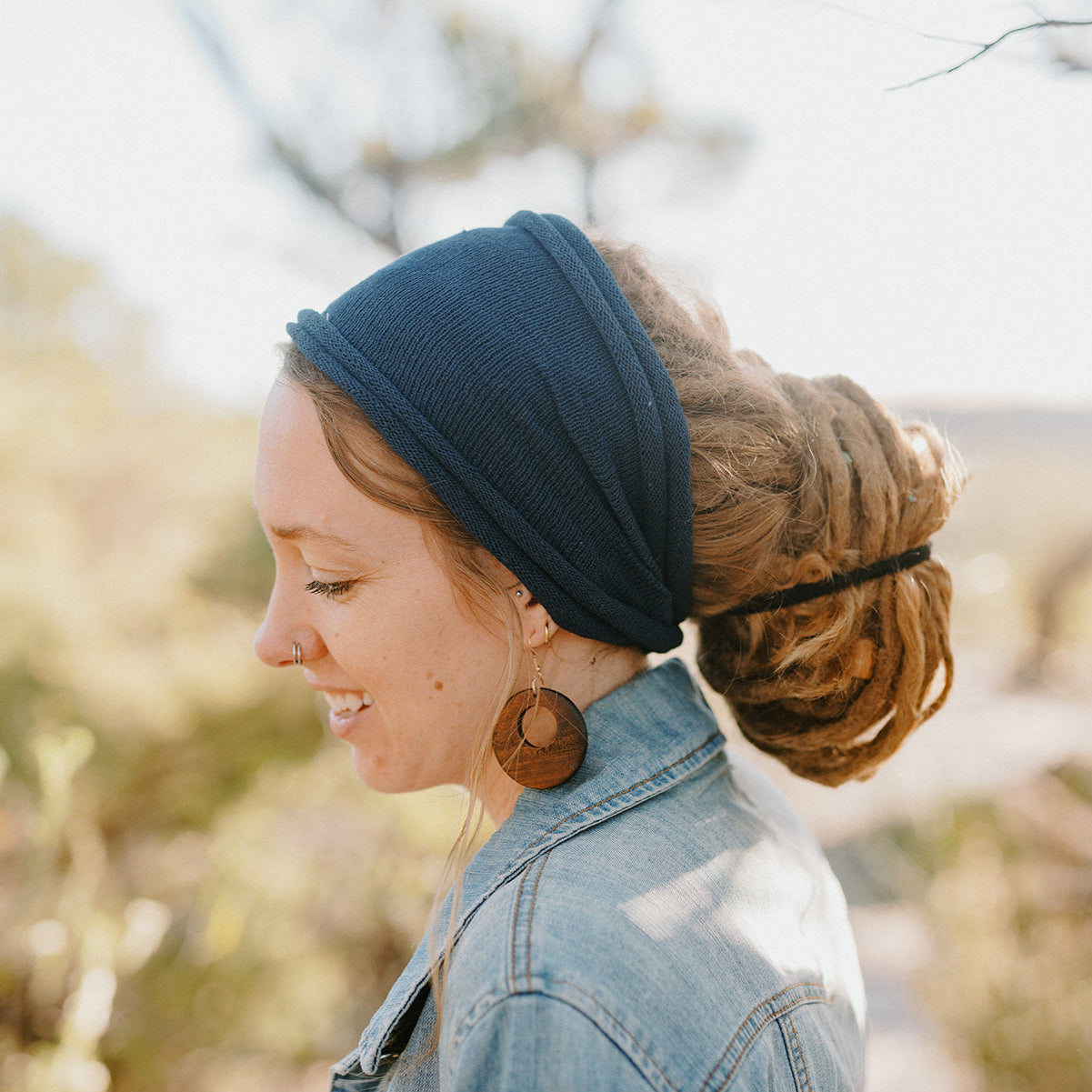 Woman wearing a dark double loop cotton headband outdoors with blurred natural background