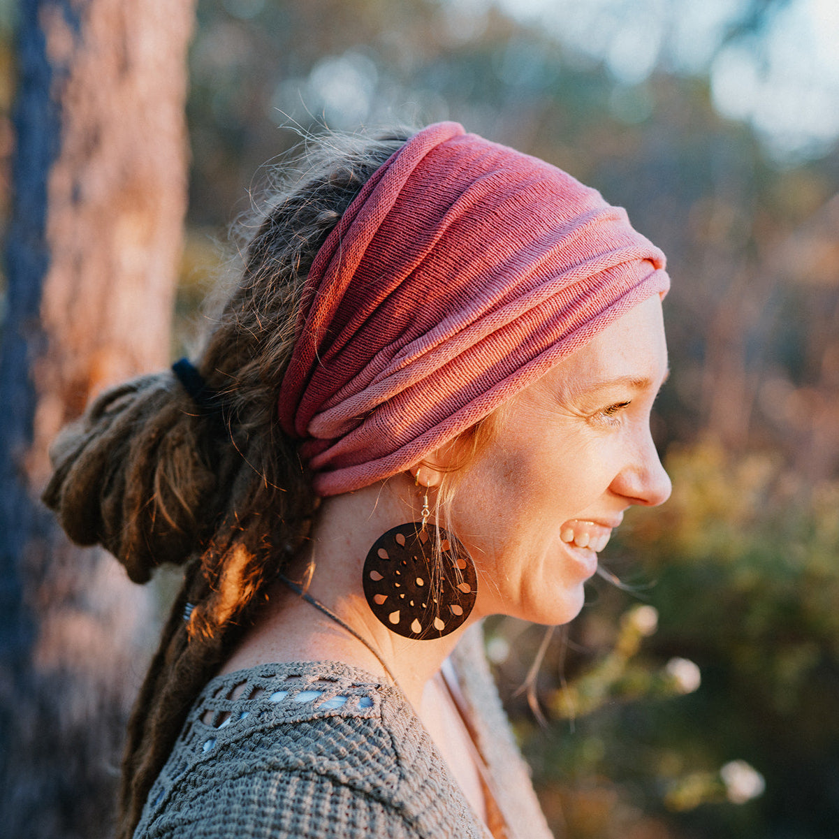 Woman wearing a pink double loop cotton headband and large earrings outdoors