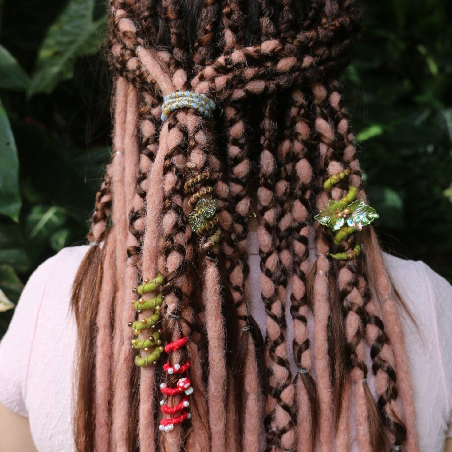 A mini spiral-shaped dreadlock tie, a spiralock, with a blue and gold pattern, placed in dreadlocks.