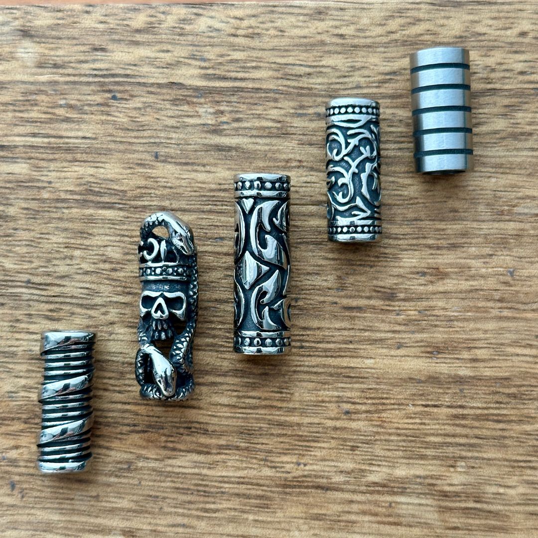 Set of 5 stainless steel tube beads on a wooden background