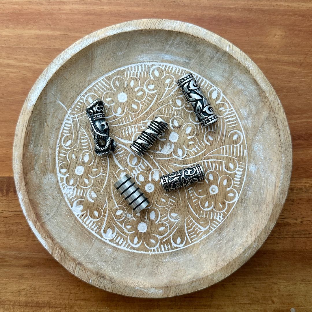 Set of 5 stainless steel tube beads on a wooden background