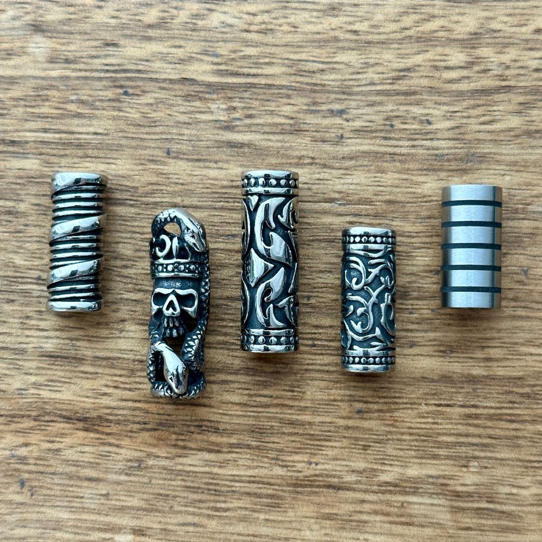 Set of 5 stainless steel tube beads on a wooden background