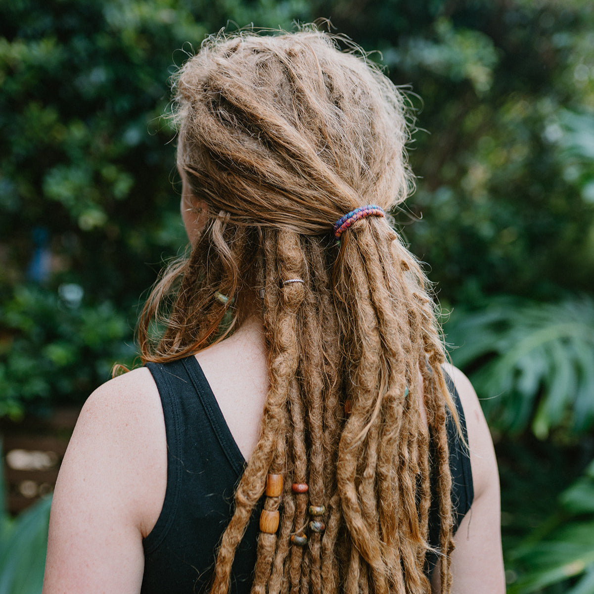 A mini spiral-shaped dreadlock tie, a spiralock, with a blue and red pattern, placed in dreadlocks.