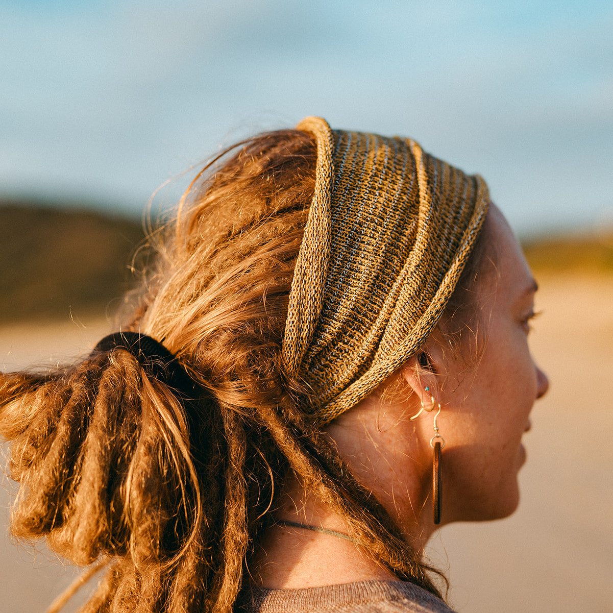 Woman with a stretchy headband on a beach at sunset
