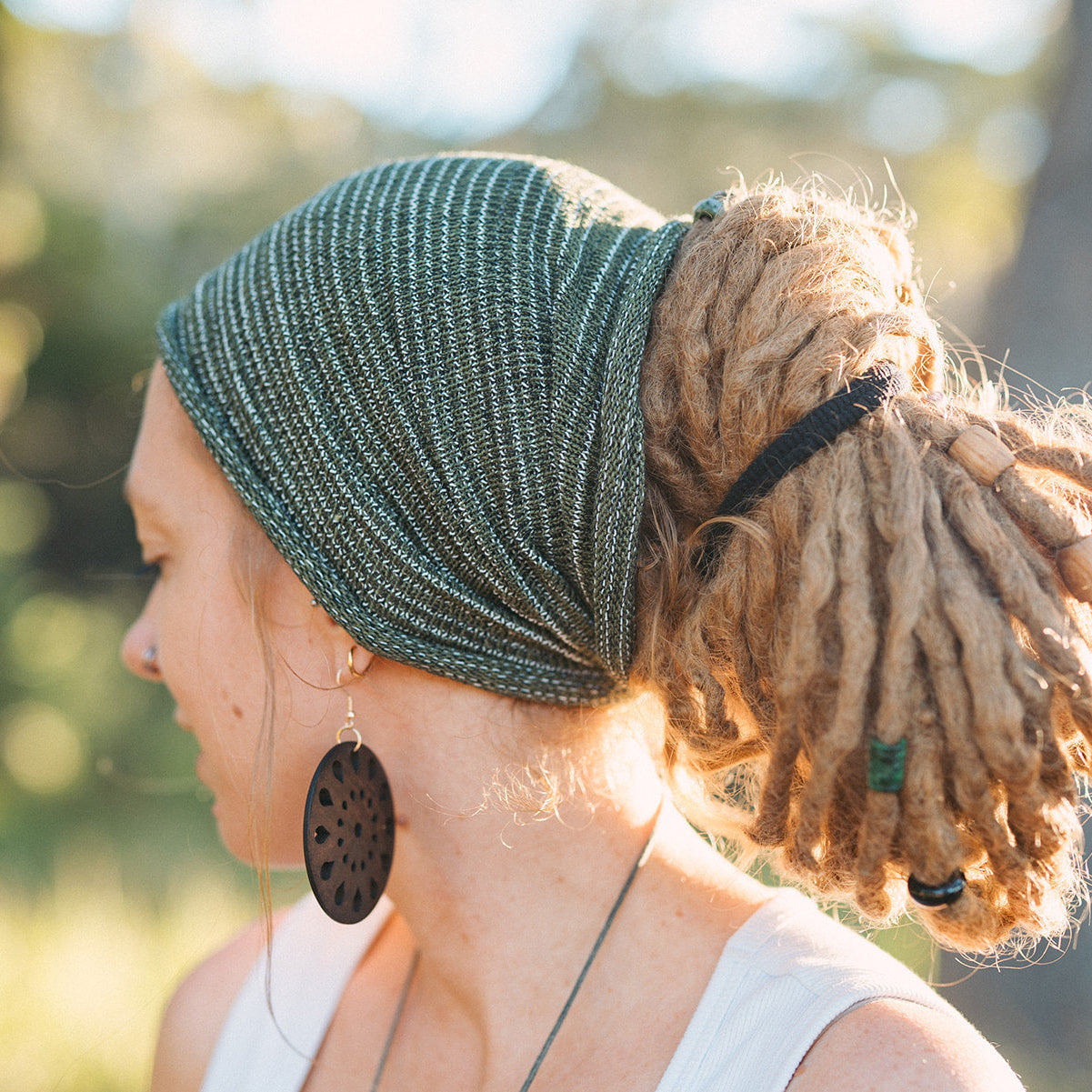 Person with green headscarf and dreadlocks in a natural setting