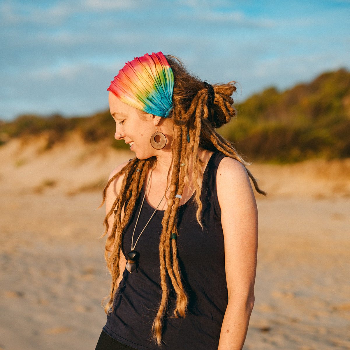 Person with colourful headband and dreadlocks standing on a beach