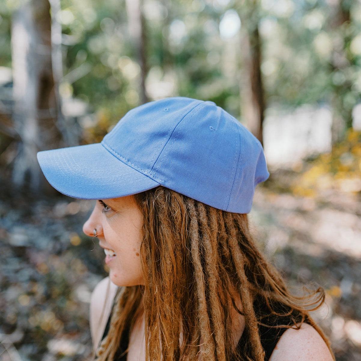 Person wearing a blue cap in a forest setting