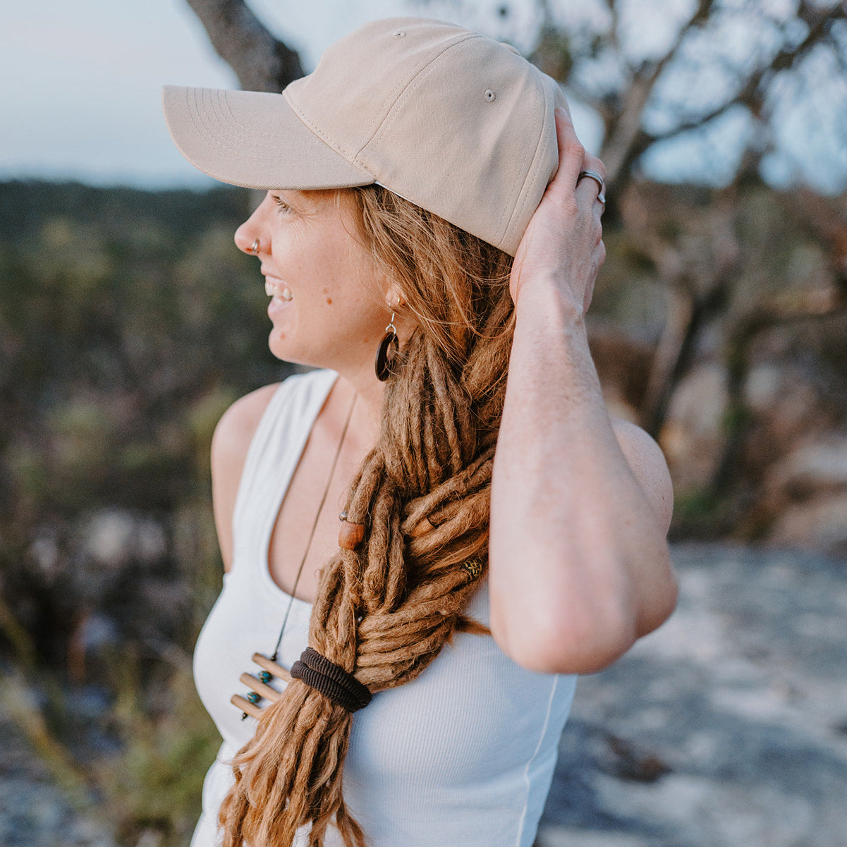 Woman with long braided hair wearing a beige cap outdoors