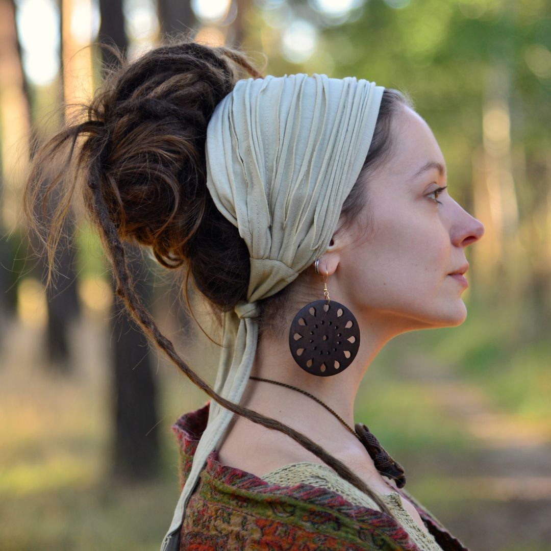 Woman with a headscarf and earrings in a forest setting
