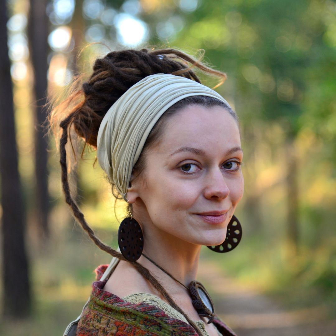 Woman with dreadlocked hair and headband in a forest setting