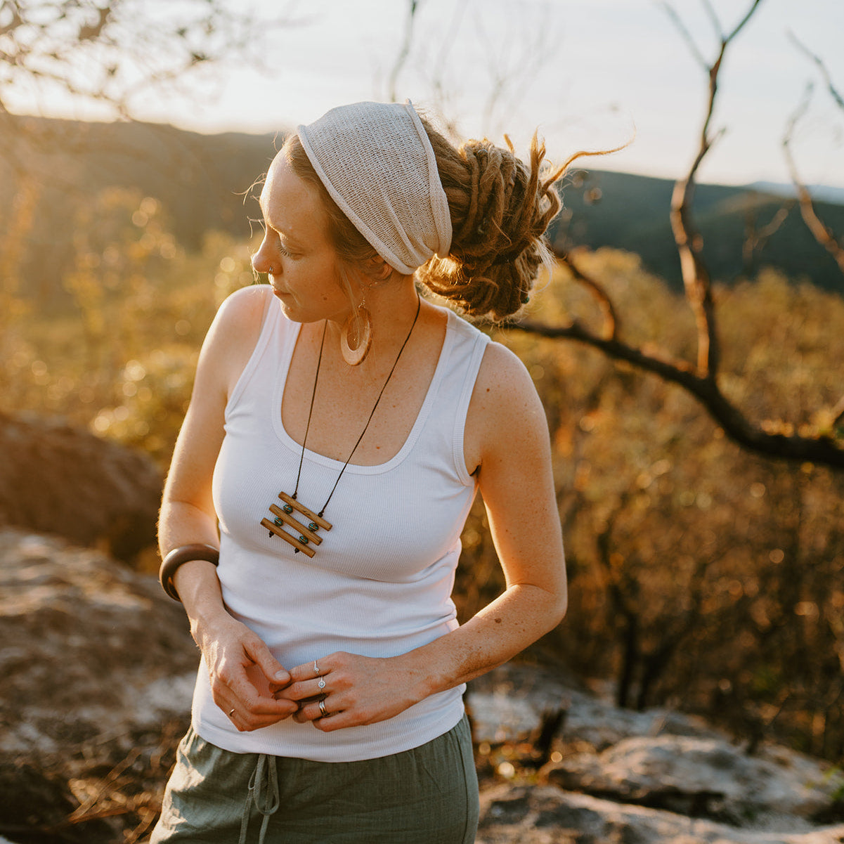 Woman wearing a cotton headband standing outdoors in a natural setting with mountains in the background