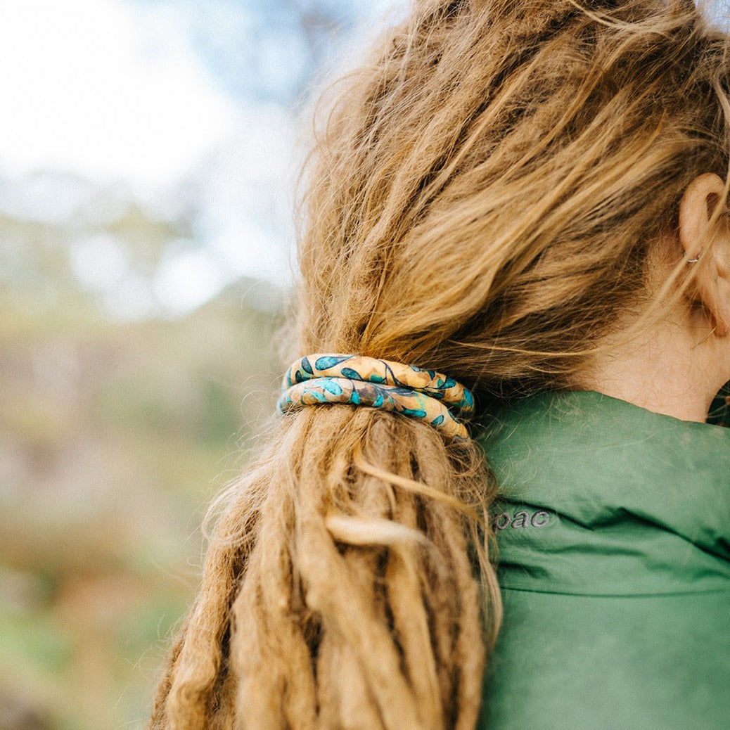 A spiral-shaped dreadlock tie, a spiralock, with a blue and orange pattern, placed in a ladies hair
