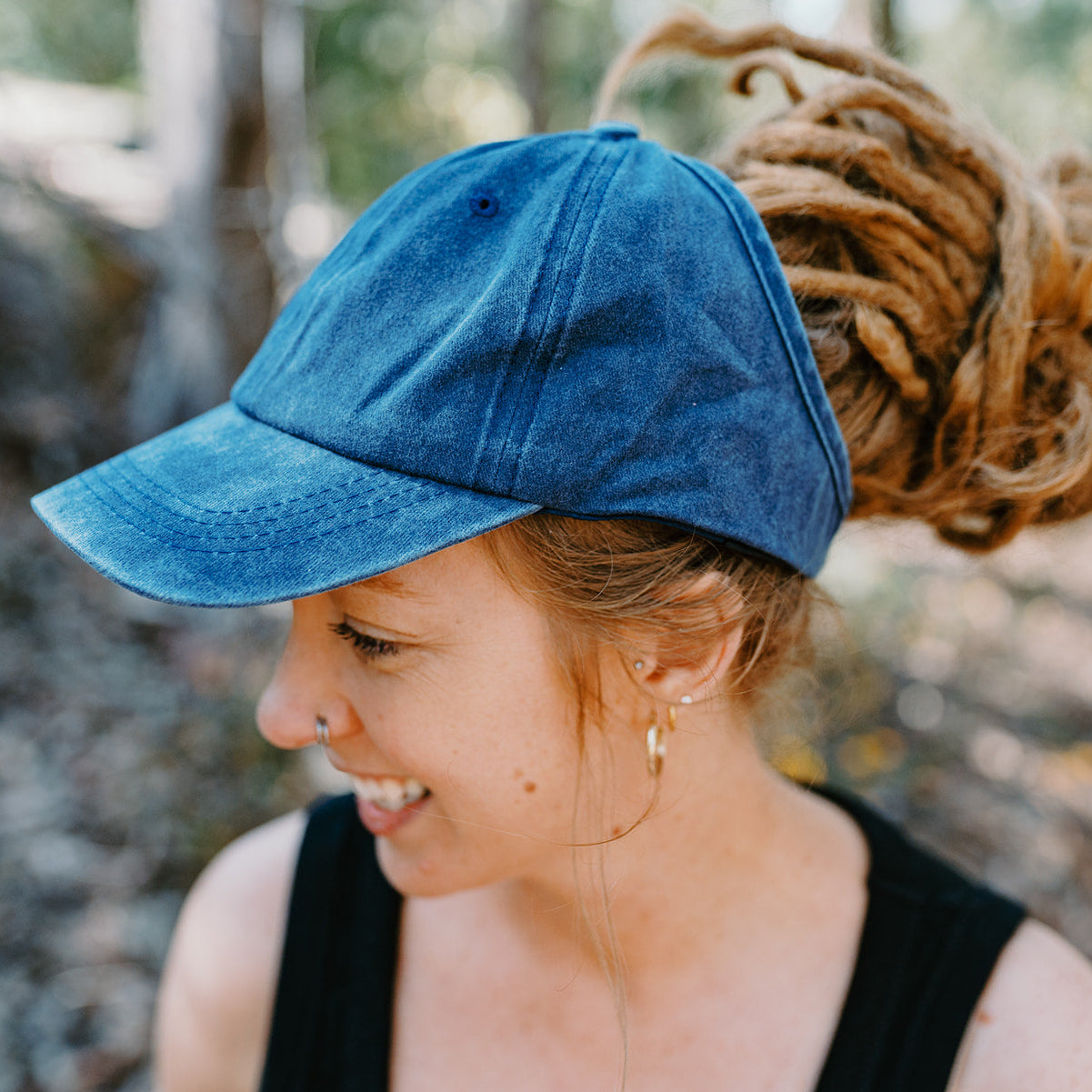 Person wearing a blue cap outdoors with a blurred natural background