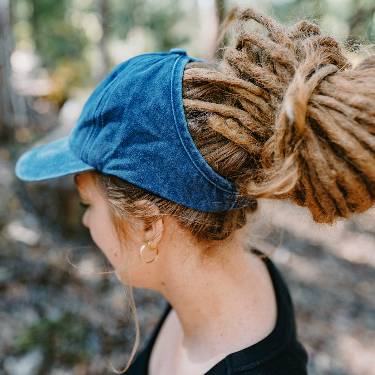 Person wearing a blue backless cap with a blurred natural background