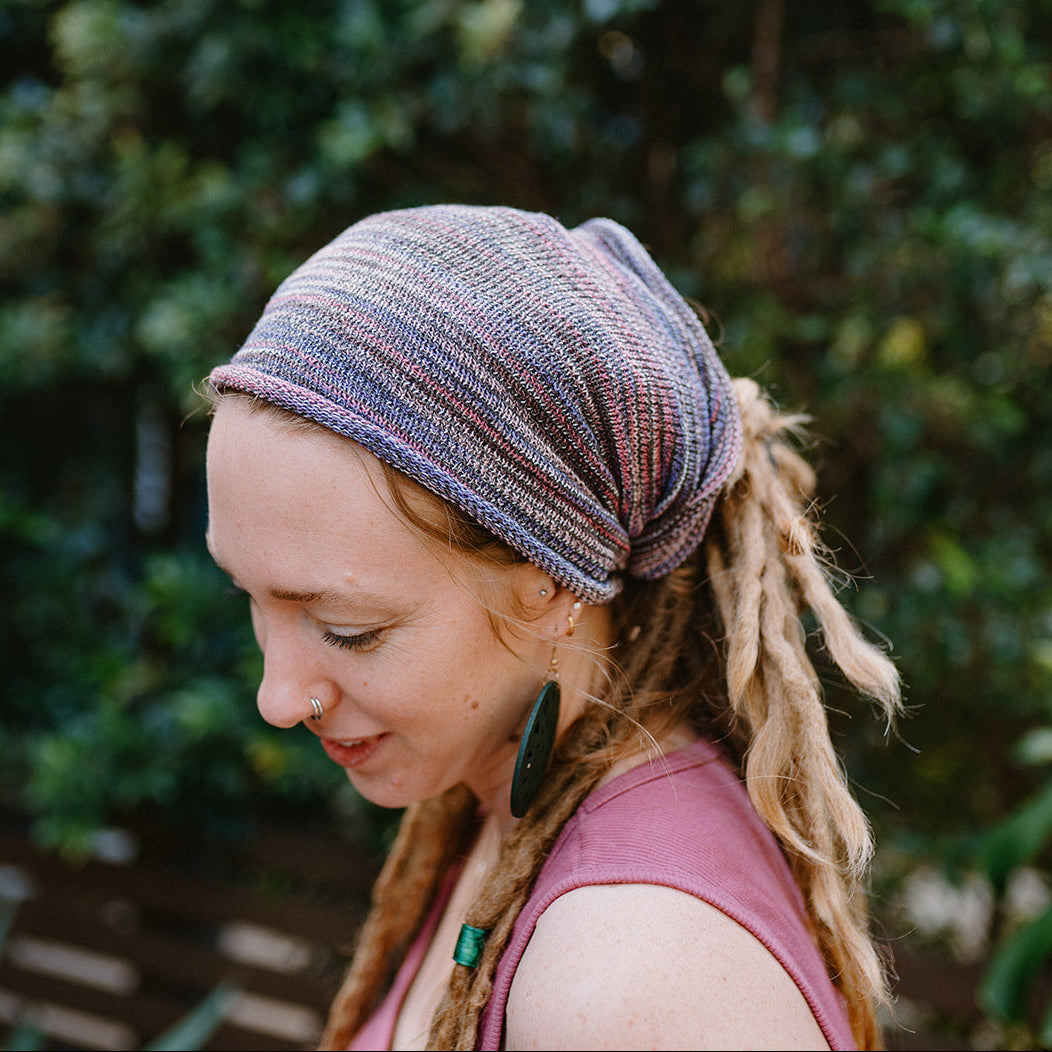 Woman wearing a patterned headscarf with green foliage in the background