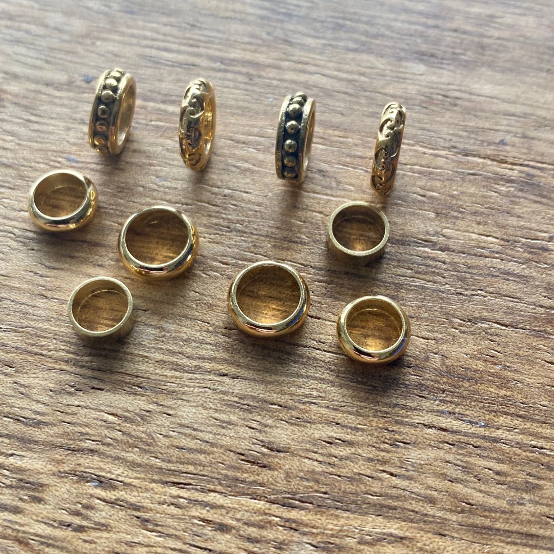 Golden stainless steel dread rings set of 10 dreadlock beads on a wooden background