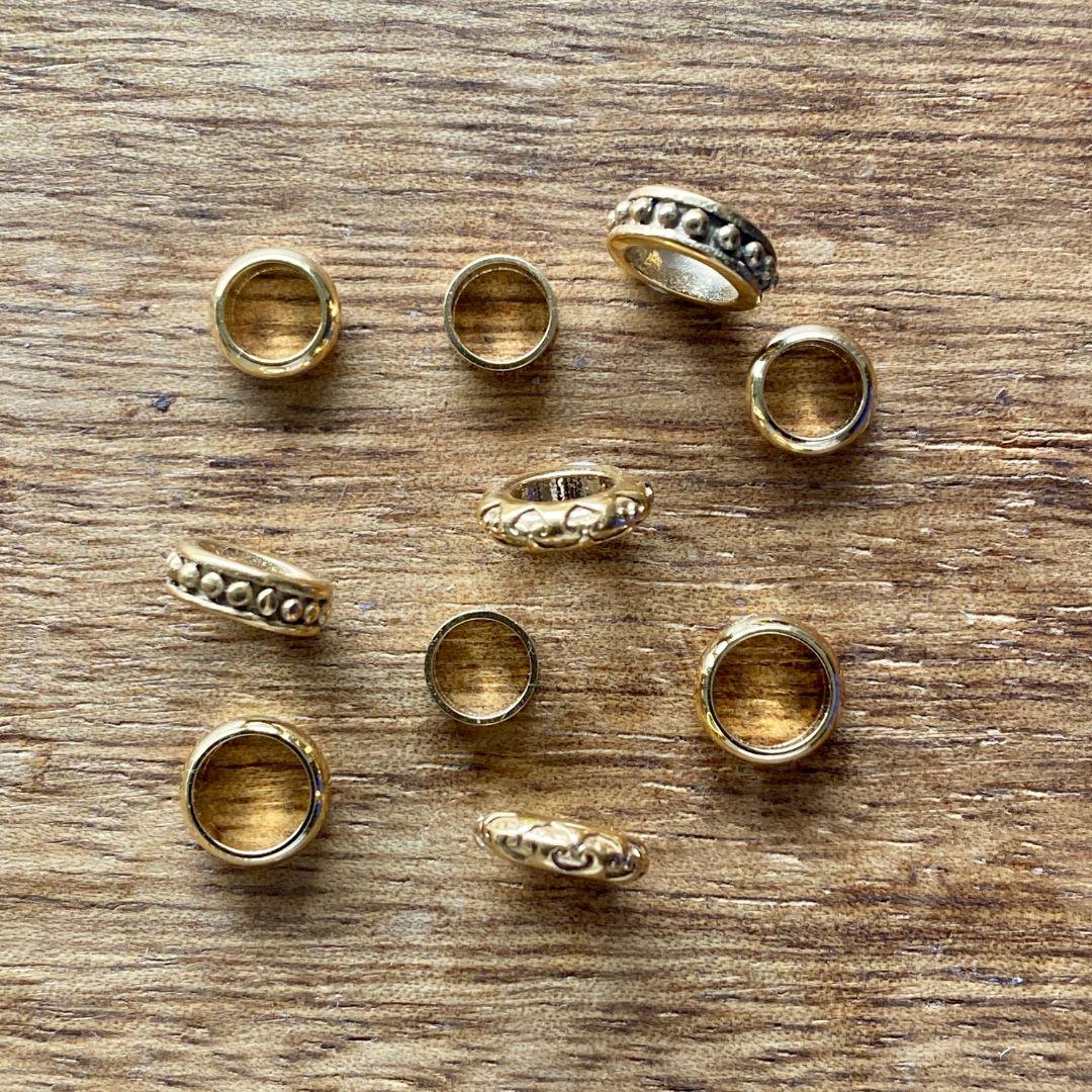 Gold dread rings with various designs on a wooden surface