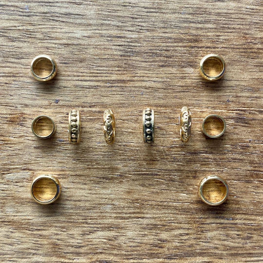 Gold dreads rings of various designs on a wooden surface