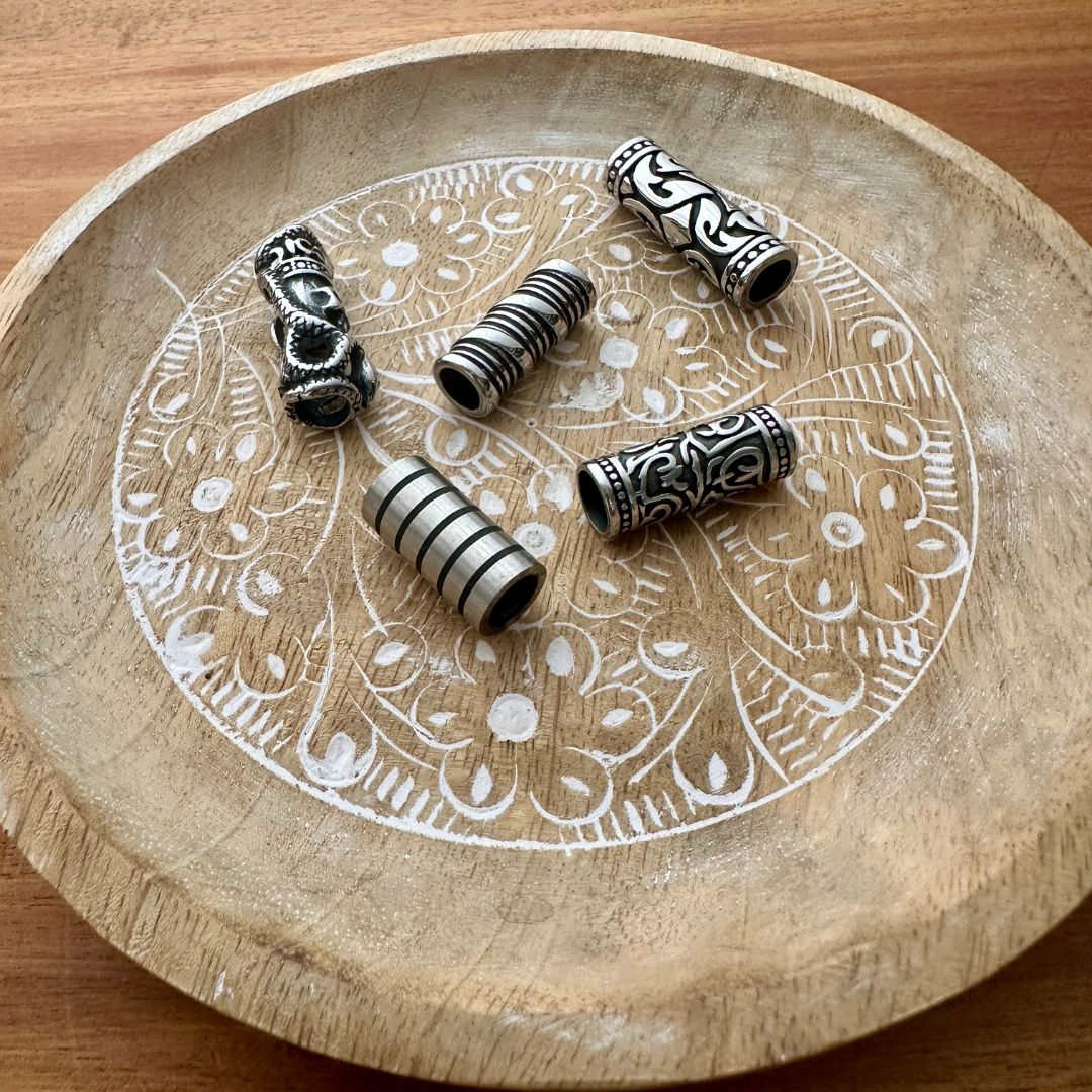 Set of 5 stainless steel tube beads on a wooden background