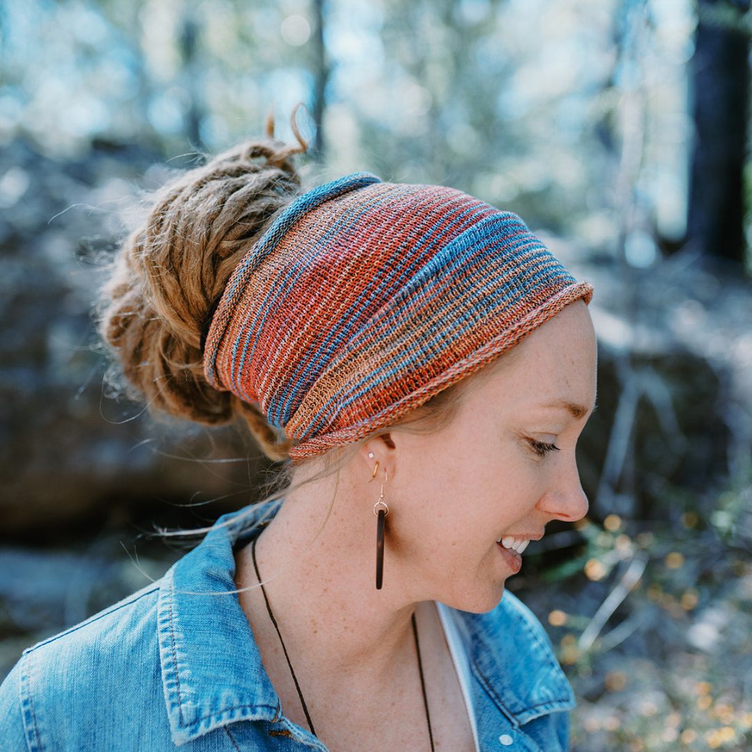 A person wearing a Orange red and blue wide cotton headband.